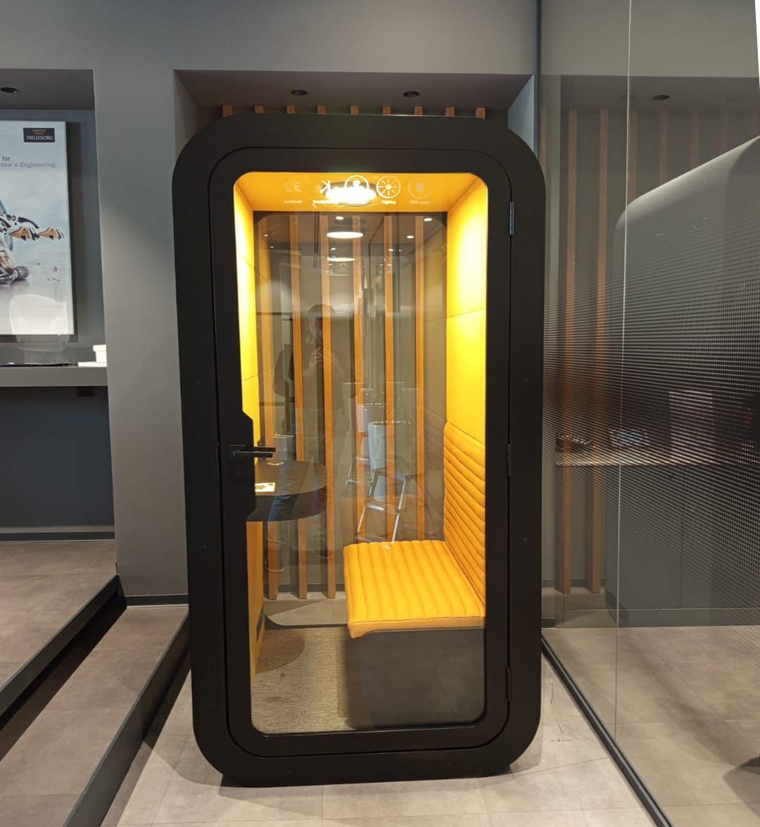 Black work pod with yellow upholstered bench seat and desk